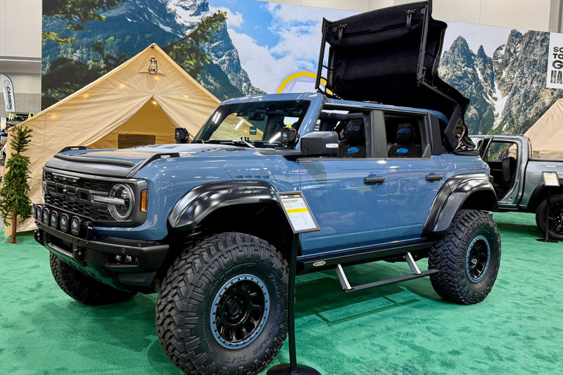 a blue Ford Bronco Raptor on display at a car show.