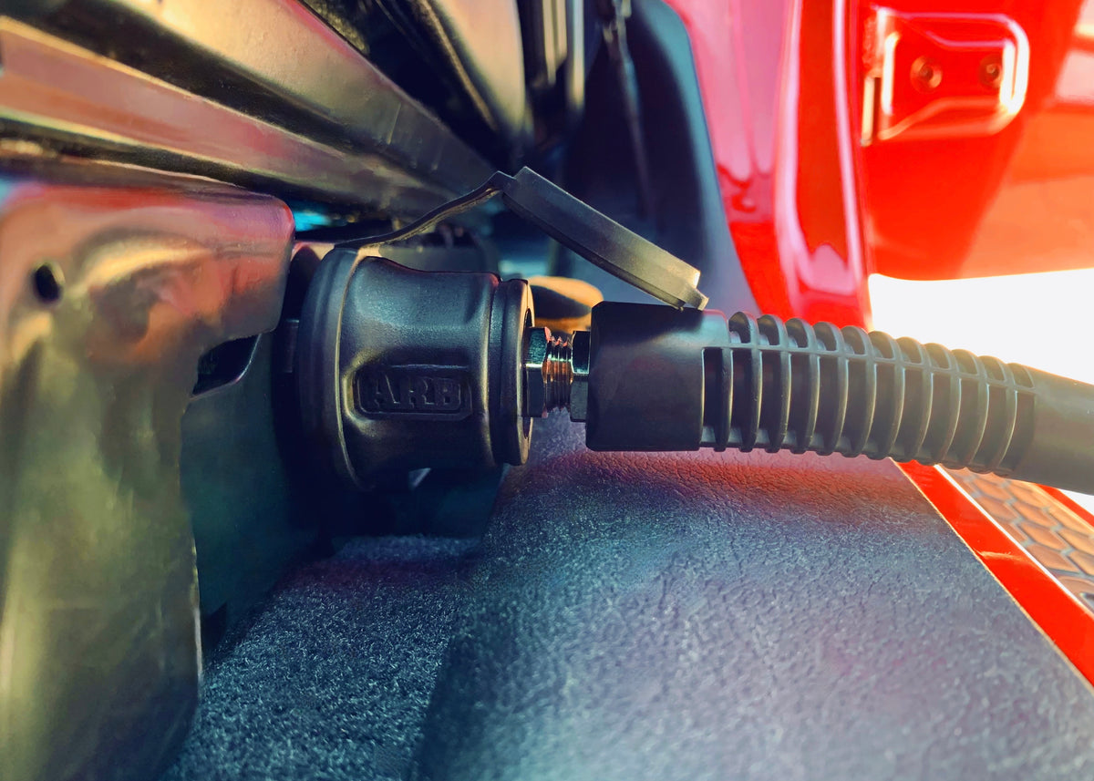 Close-up of an air hose on a vehicle, with a red door in the background.