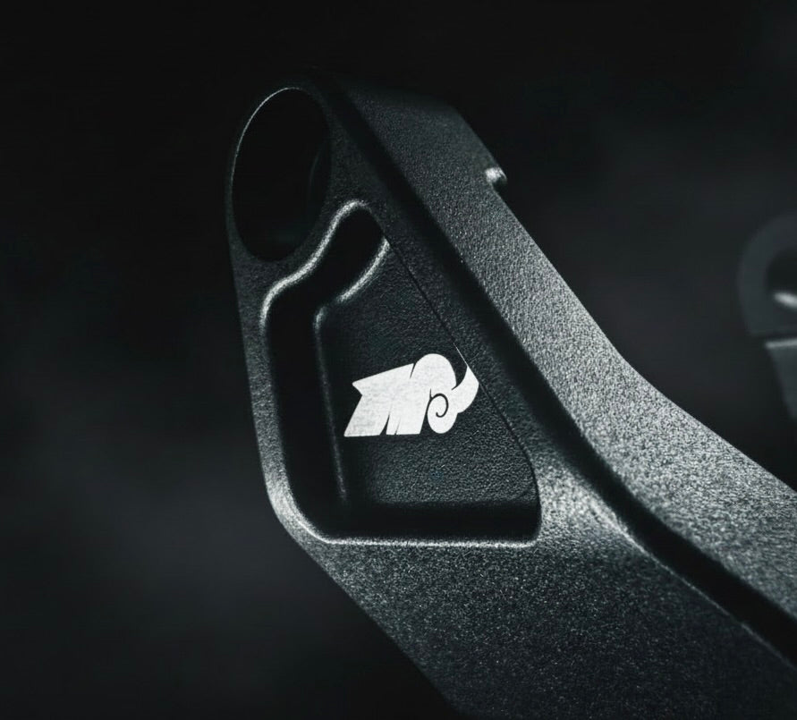 Close-up of a black metal component with a logo on a dark background